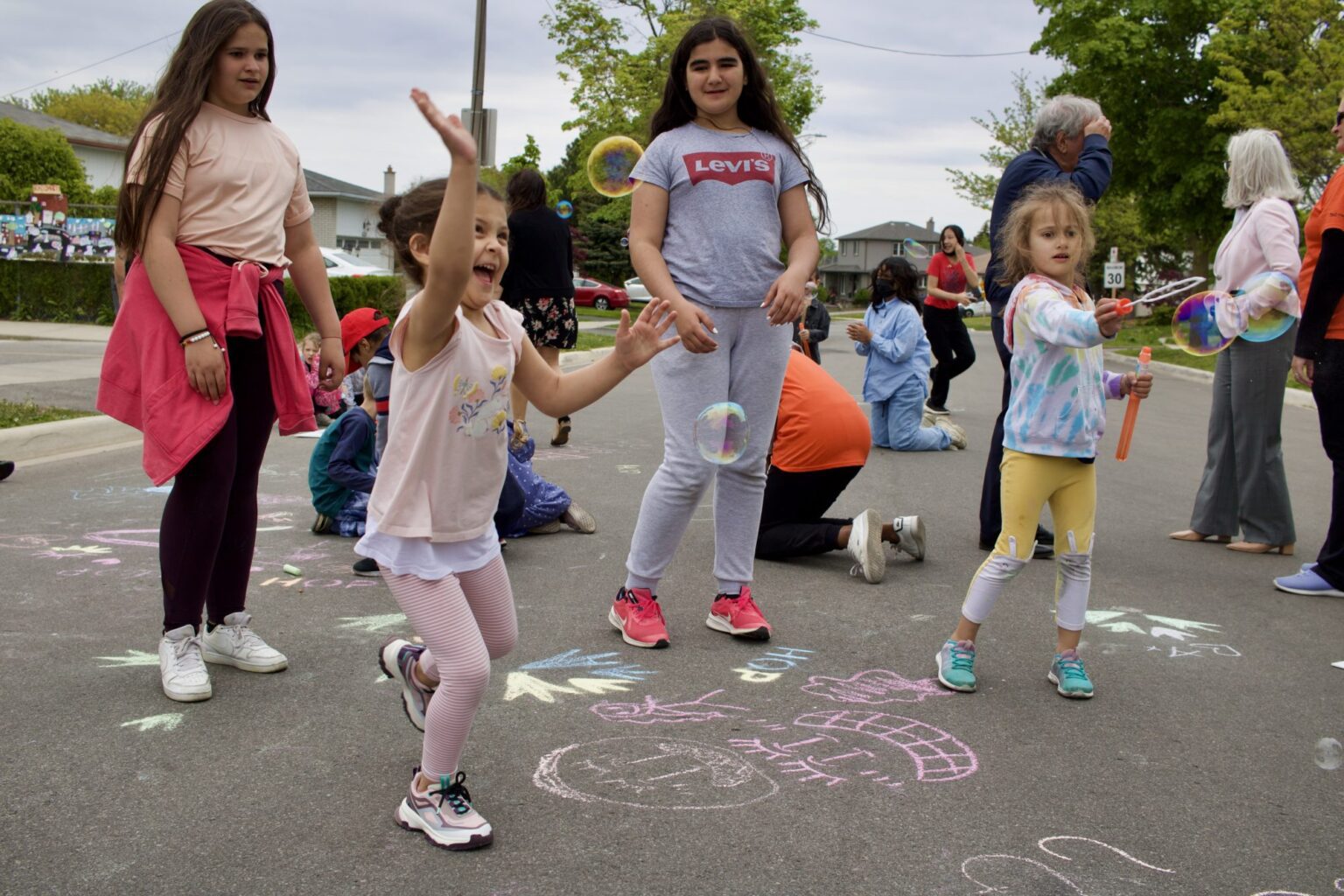 kids playing on pavement covered in sidewalk chalk