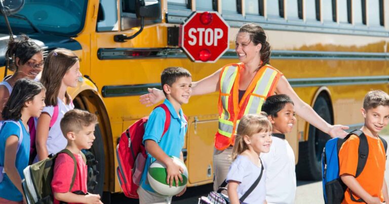 Kids guided out of a school bus by a crossing guard