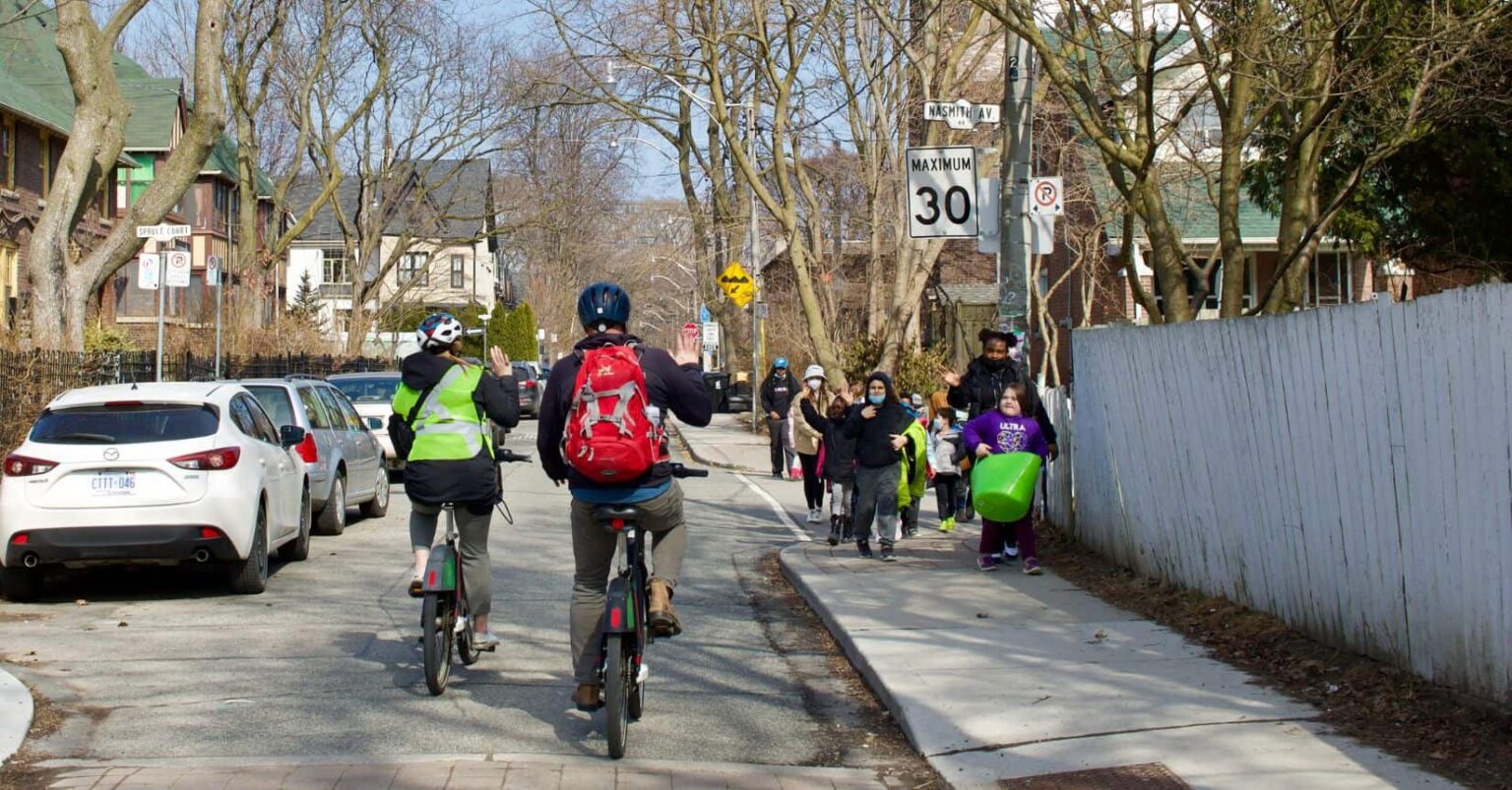 Cyclists waving to student “walking school bus” in Toronto, Ontario (Photo by: Green Communities Canada)