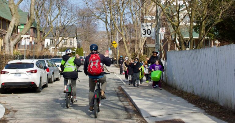 Cyclists waving to student “walking school bus” in Toronto, Ontario (Photo by: Green Communities Canada)
