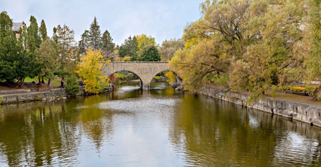 River in Stratford Ontario with forest and bridge.