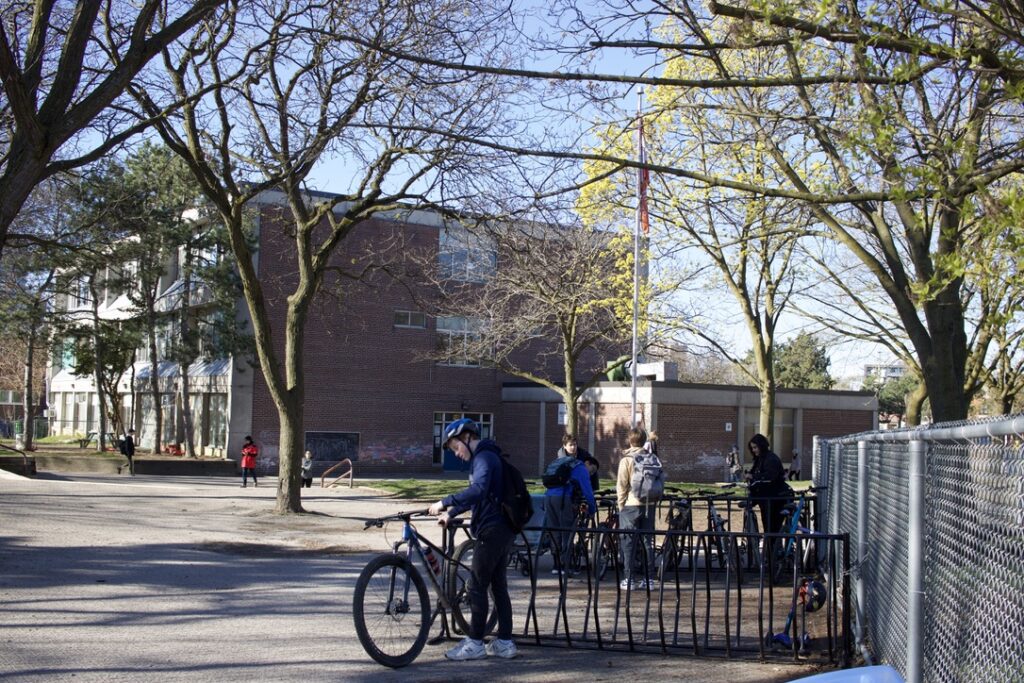 A crossing guard assists children and families walking across a marked crosswalk on the way to school.