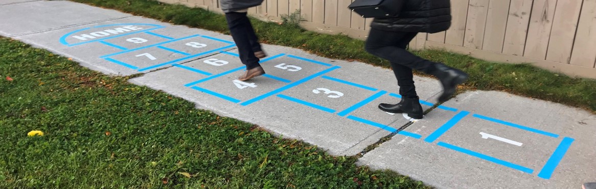 Two people playing on a sidewalk hopscotch game.