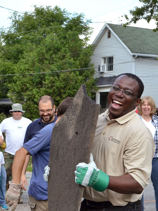 Smiling volunteer holds a large slab of asphalt during a Depave Paradise event.