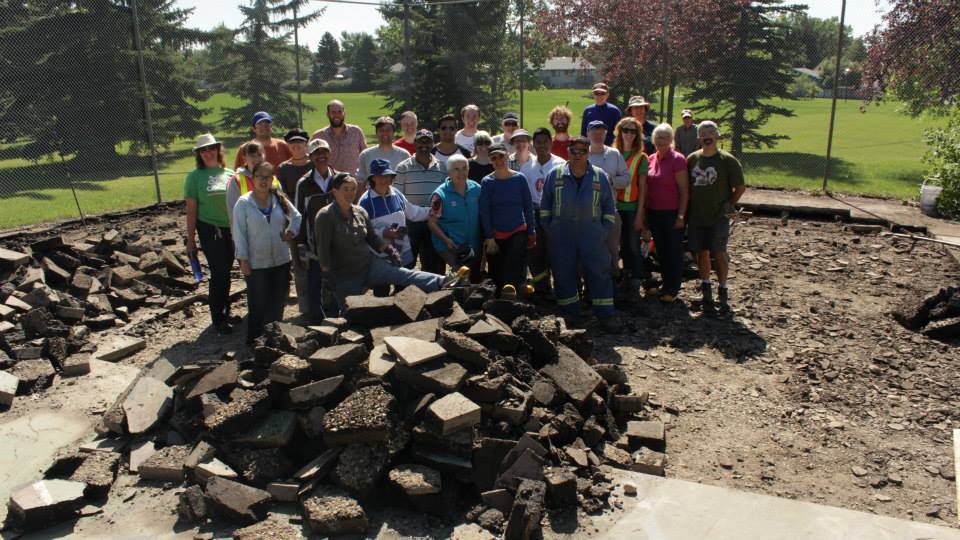 Team photo of a community group together posing in front of a rain garden project in progress.
